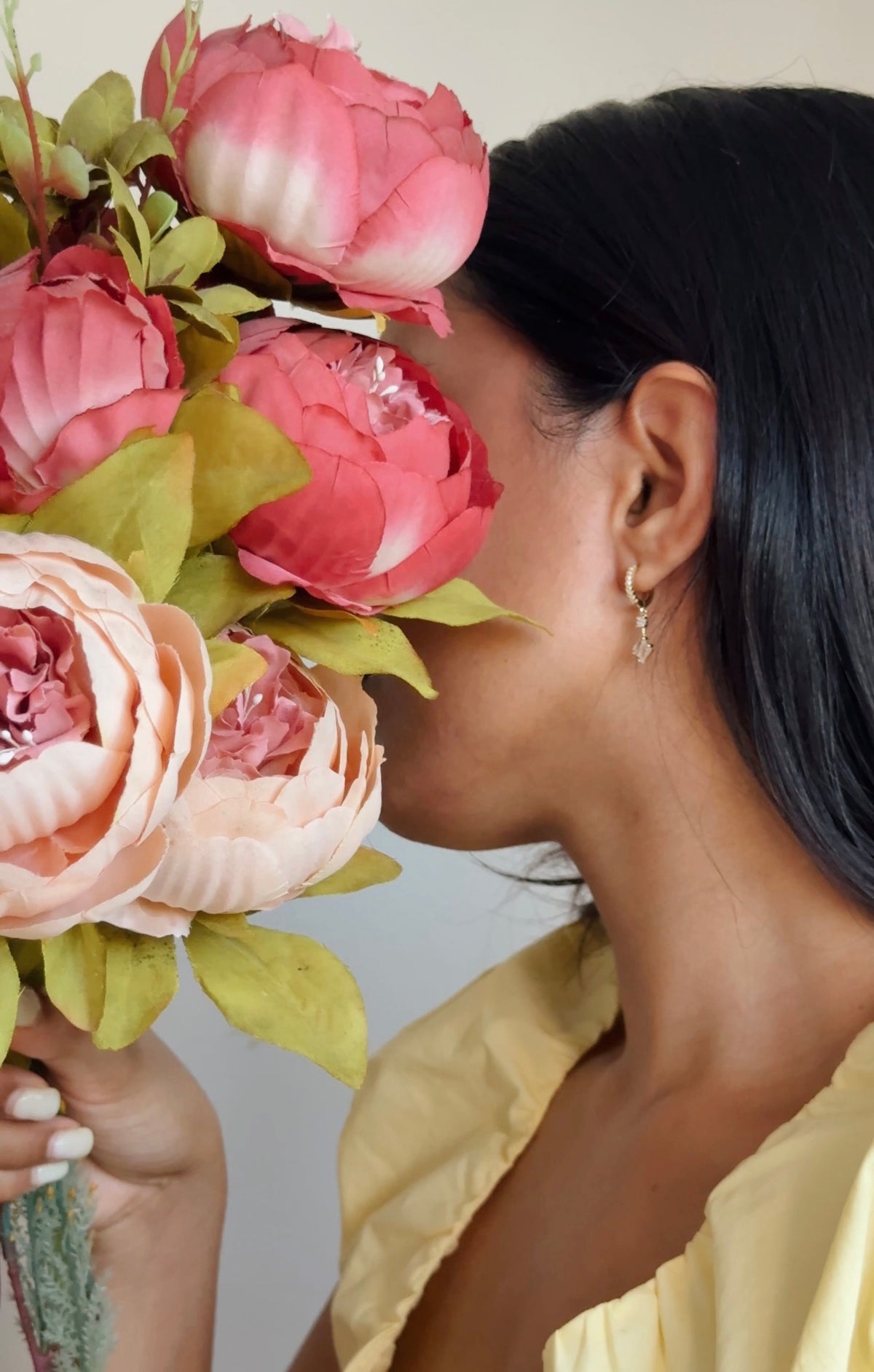 Woman wearing gold Sunbeam Huggies, holding a bouquet of pink peonies